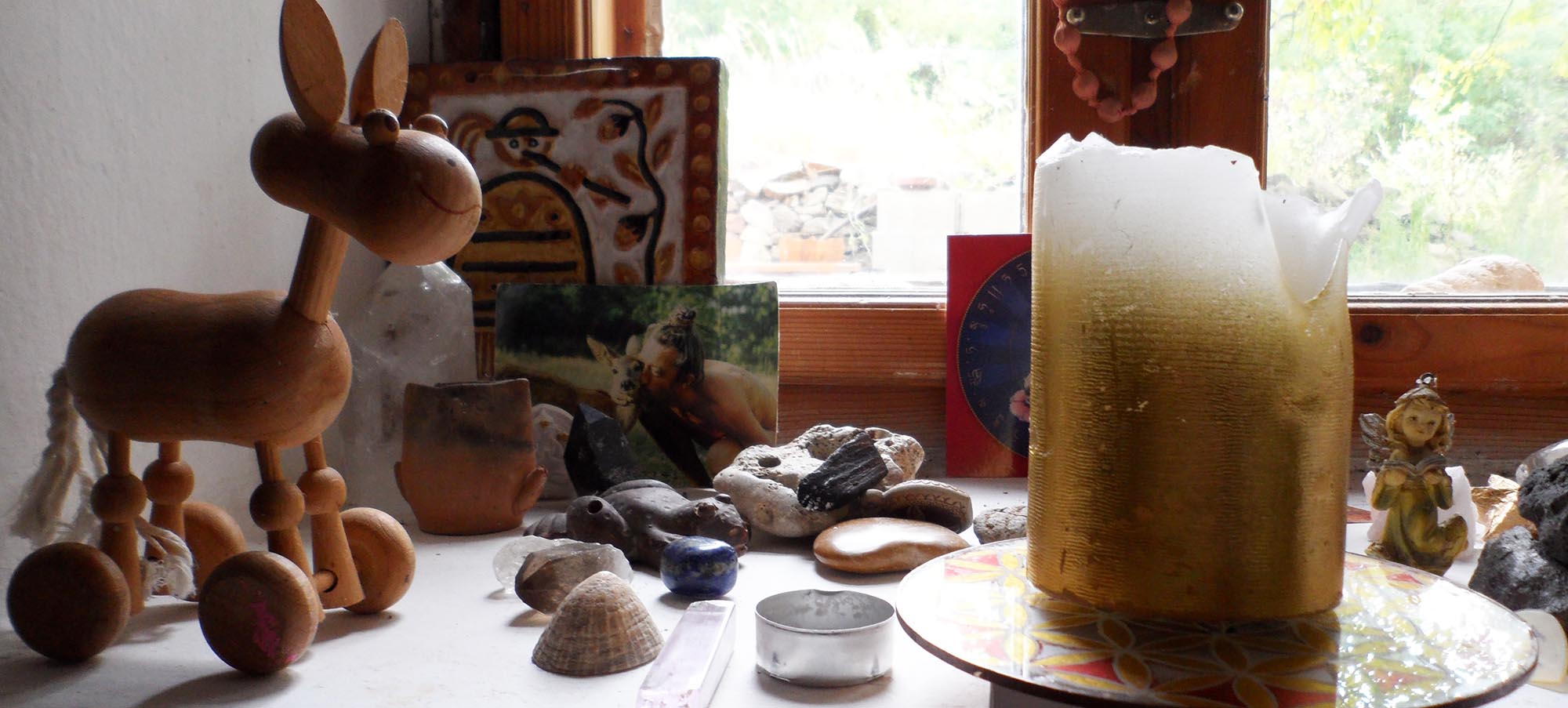 Auf der Fensterbank ein Holzpferd, ein Foto von Istvan mit einem Reh und eine Kerze. Haus von Istvan Sky (István Sky), Napfényszentély in Ungarn, in Szentbékkállá.