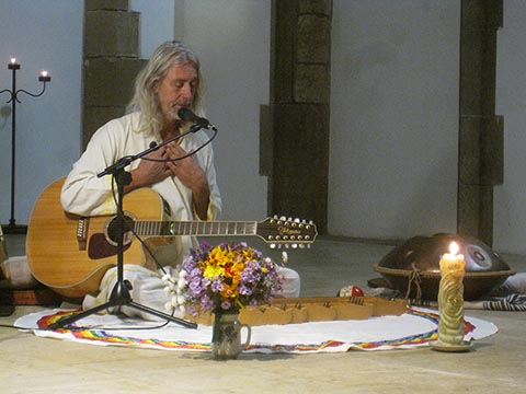 Konzert von István Sky in der St.-Martins-Kirche in Prag. István mit Gitarre, daneben Blumen in einer Vase und eine brennende Kerze. 06.10.2023.