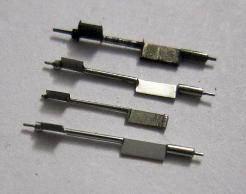 Antique verge escapement table clock. Manufacturing the balance staff. Three newly crafted balance staffs next to the broken original. Side view.