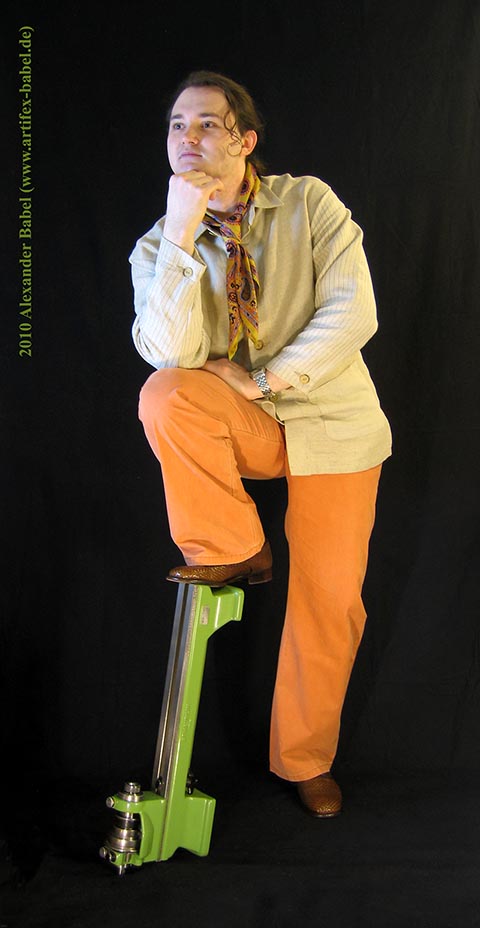 Александр Бабель крупным планом в полный рост в анфас. Нога, согнутая в колене, стоит на токарном станке Schaublin 70.