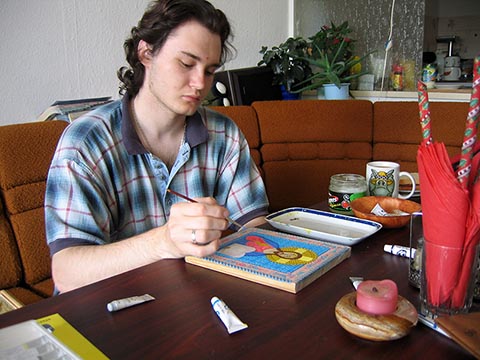 Александр Бабель за столом, пишущий икону к юбилею отца Дионисия.